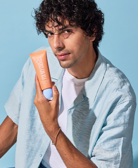 Man holding Curl Quenching Flax Seed Gelly against a blue background