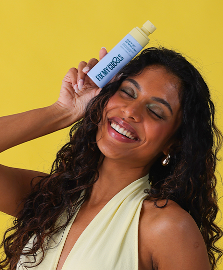 Woman holding a bottle of Ready, Set, Refresh Spray against a yellow background